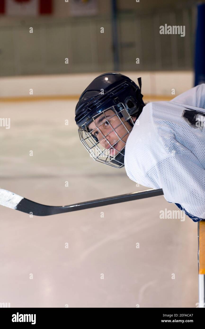 Side profile of an ice hockey player leaning over the railing of an ice ...