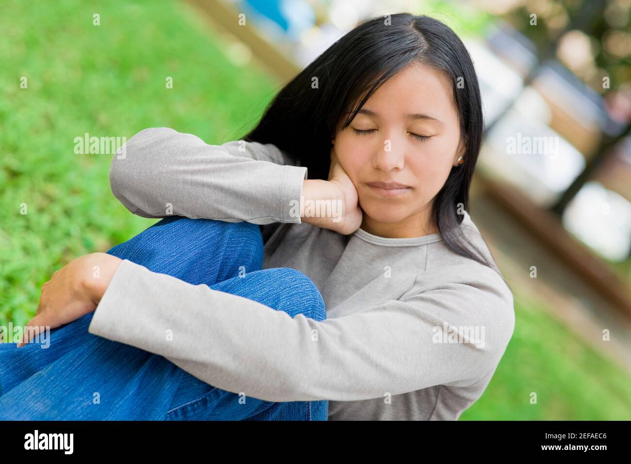Close-up of a young woman sitting with her eyes closed in a park Stock ...
