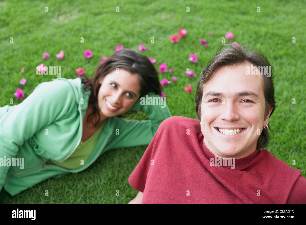 Portrait of a mid adult man lying on the grass with a young woman Stock ...