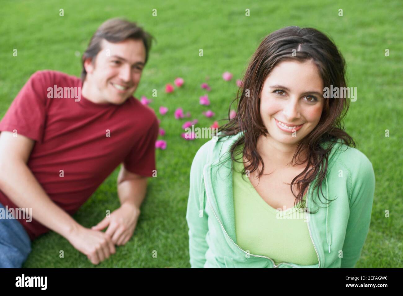 Portrait of a young woman smiling with a mid adult man lying on the ...