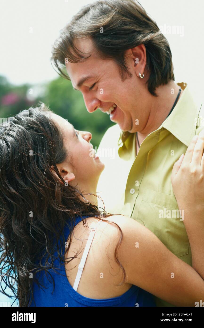 Side profile of a young woman and a mid adult man embracing each other ...
