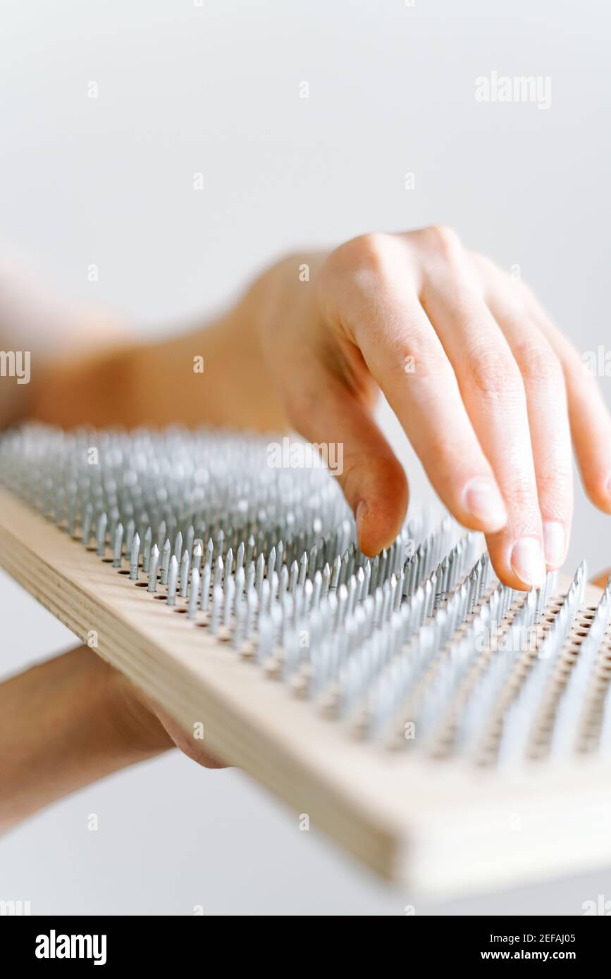 a woman of European appearance holds a wooden board with galvanized nails  and puts her hand on top of the nails of the sadhu board. trend of  self-deve Stock Photo - Alamy