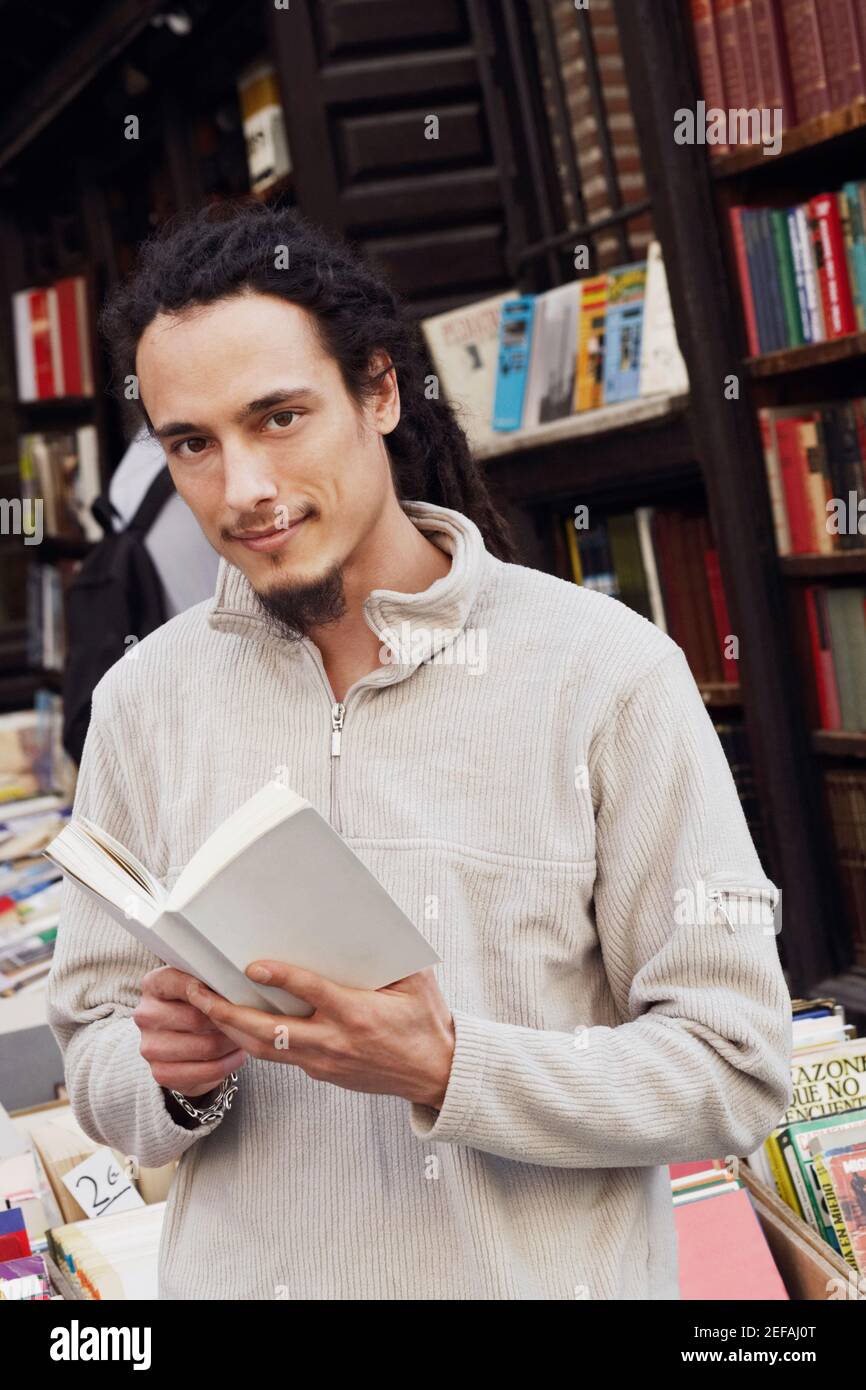 Portrait of a young man holding a book in a library Stock Photo