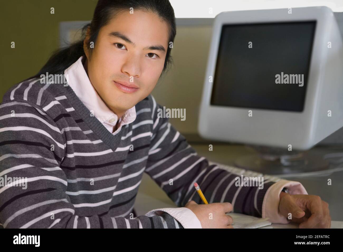 Portrait of a young man sitting in a computer lab and studying Stock ...