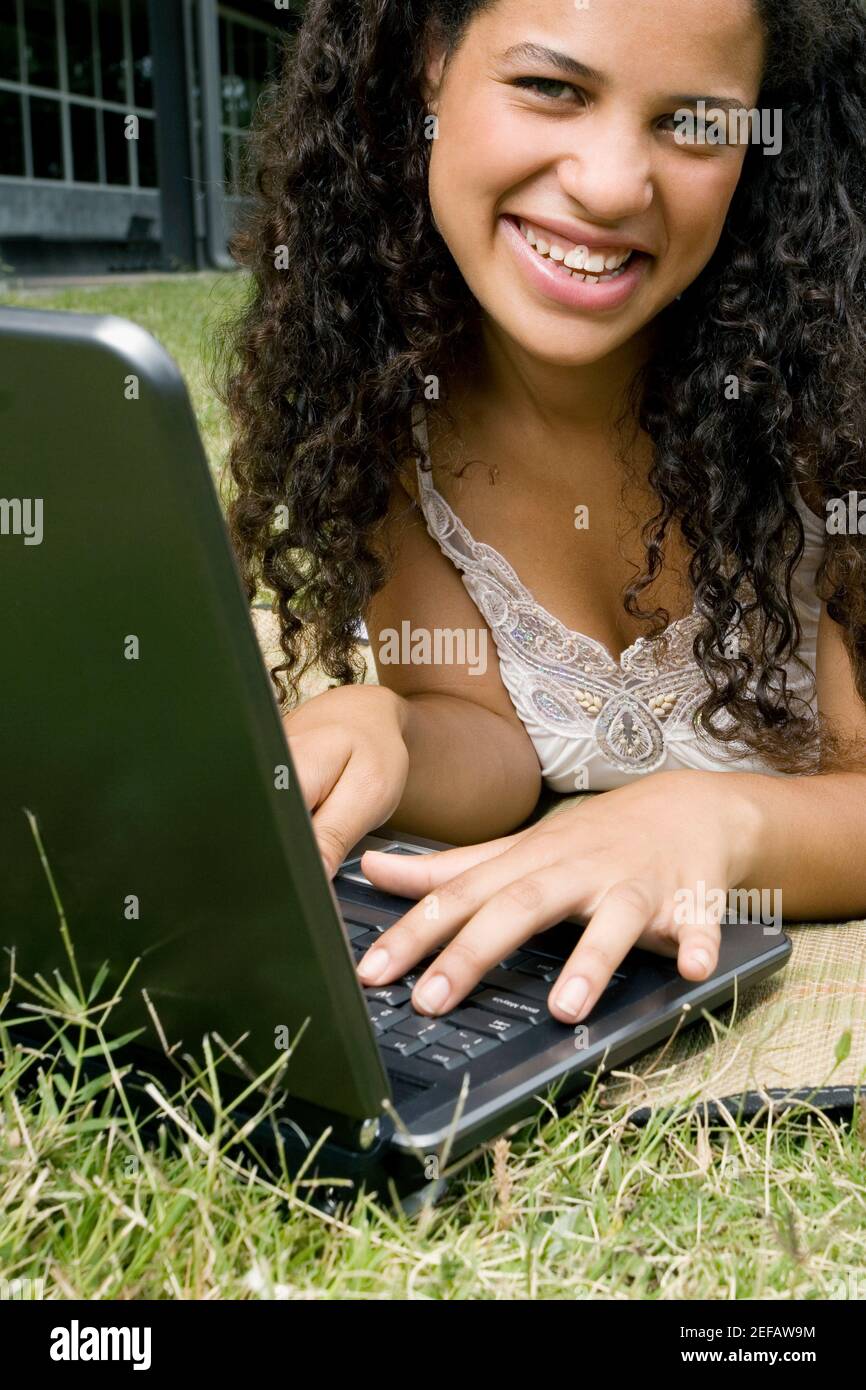 Portrait of a teenage girl working on a laptop and smiling Stock Photo