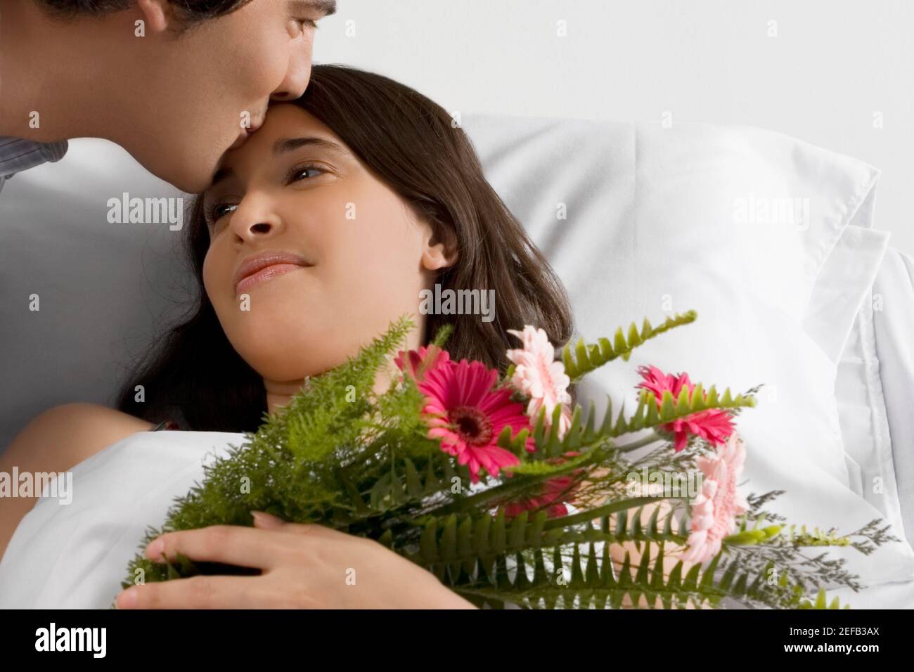 Mid adult man kissing a young woman in a hospital ward Stock Photo