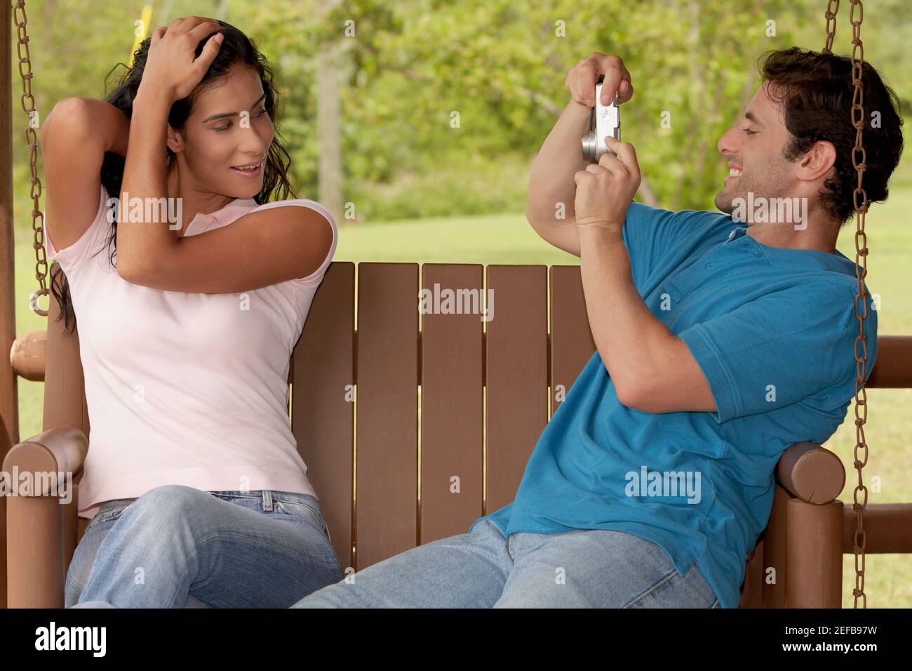 Side profile of a mid adult man photographing a young woman Stock Photo ...