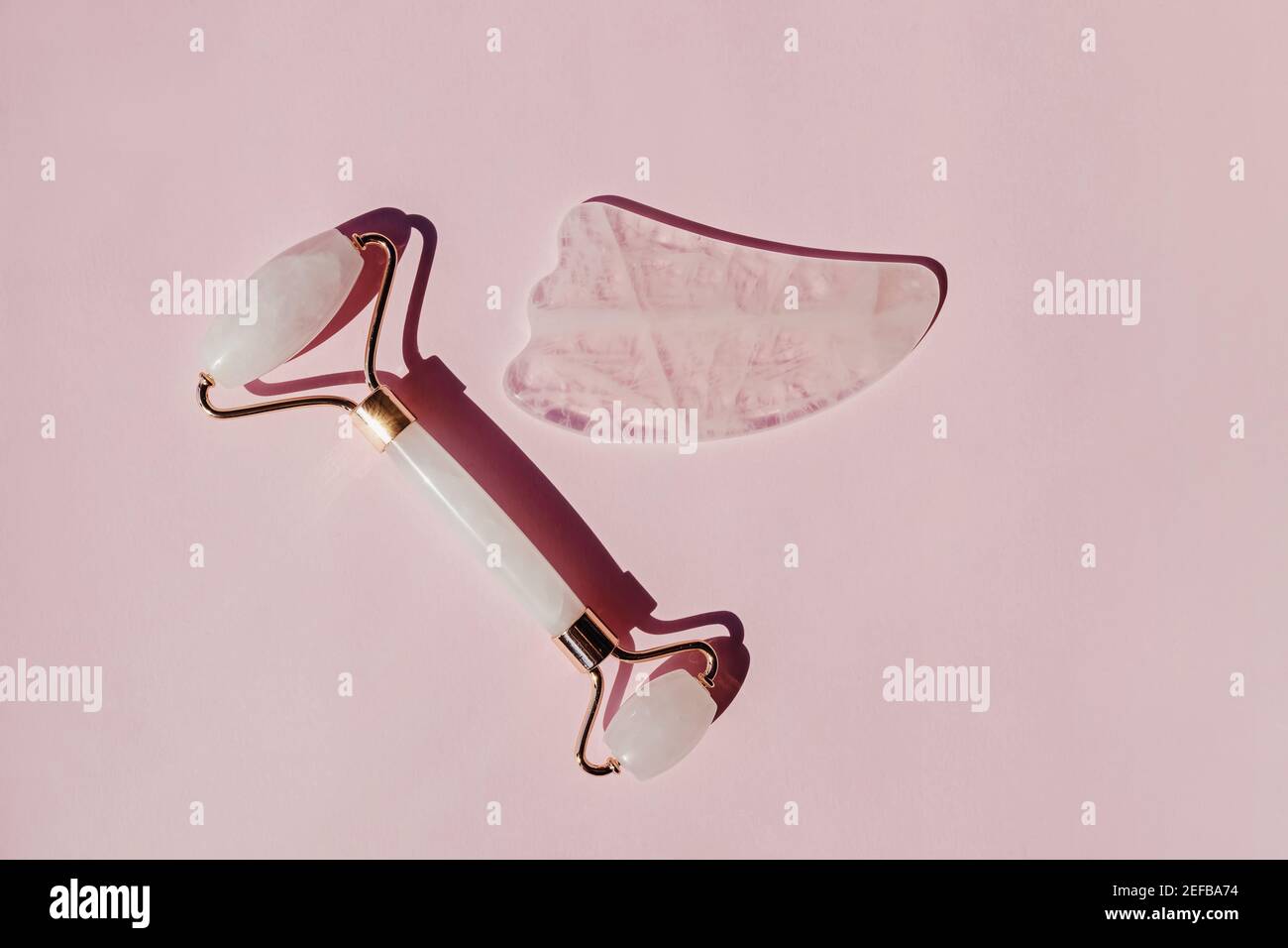 Jade roller and gua sha massage tool on pink background Stock Photo