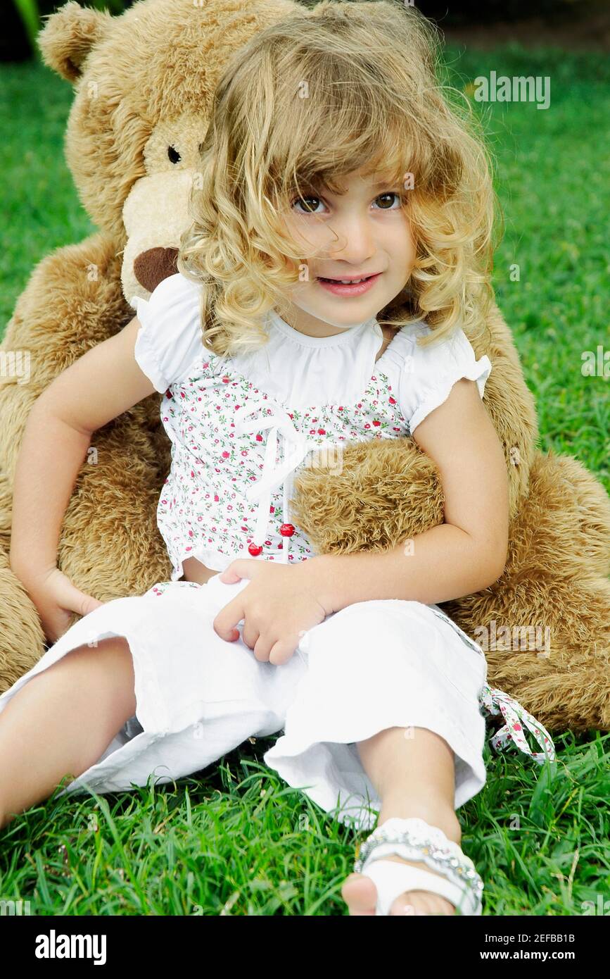 Portrait of a girl sitting on the grass with a teddy bear Stock Photo ...