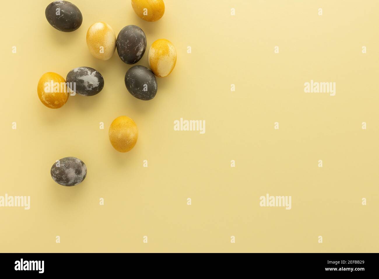 Golden and silver easter eggs scattered on yellow background, festive easter concept Stock Photo