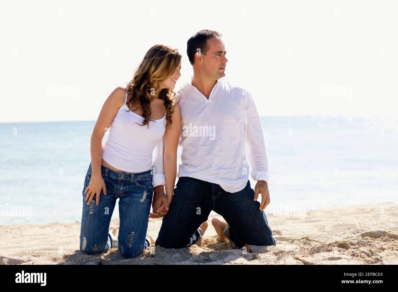 Mid adult man and a young woman kneeling with holding hands on the ...