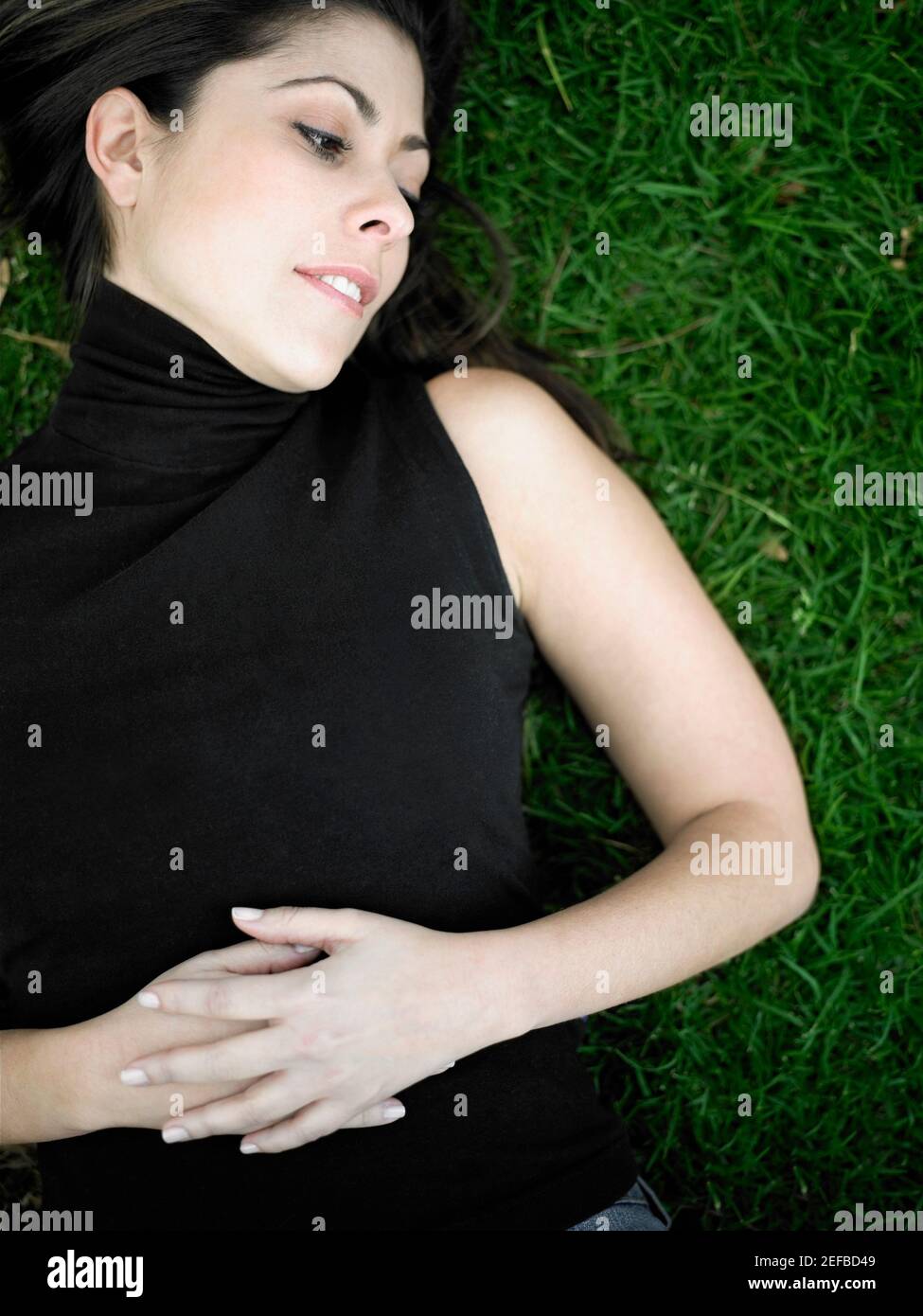 High angle view of a mid adult woman lying on a lawn Stock Photo