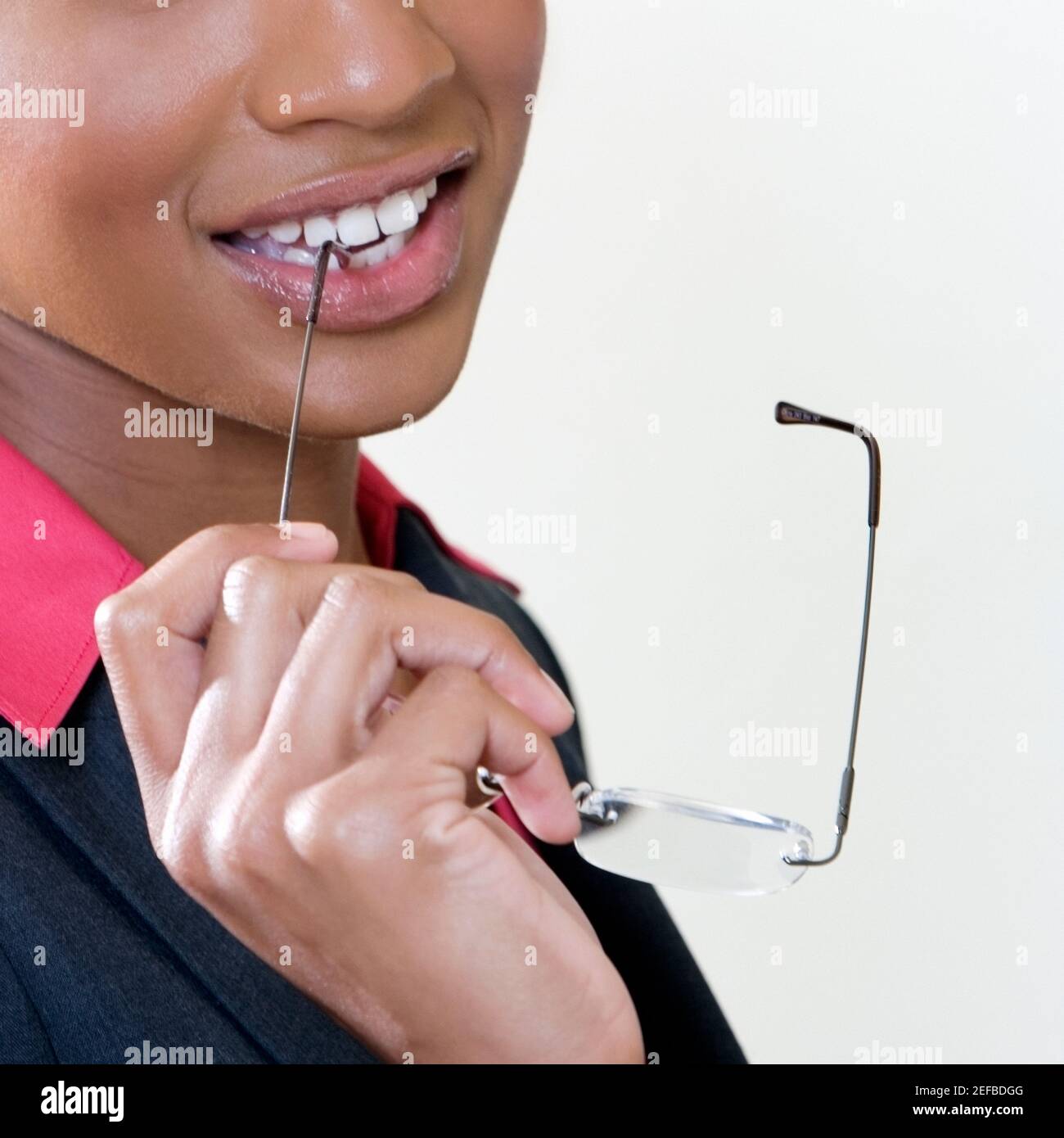 Closeup of a young woman biting the shaft of her eyeglasses Stock