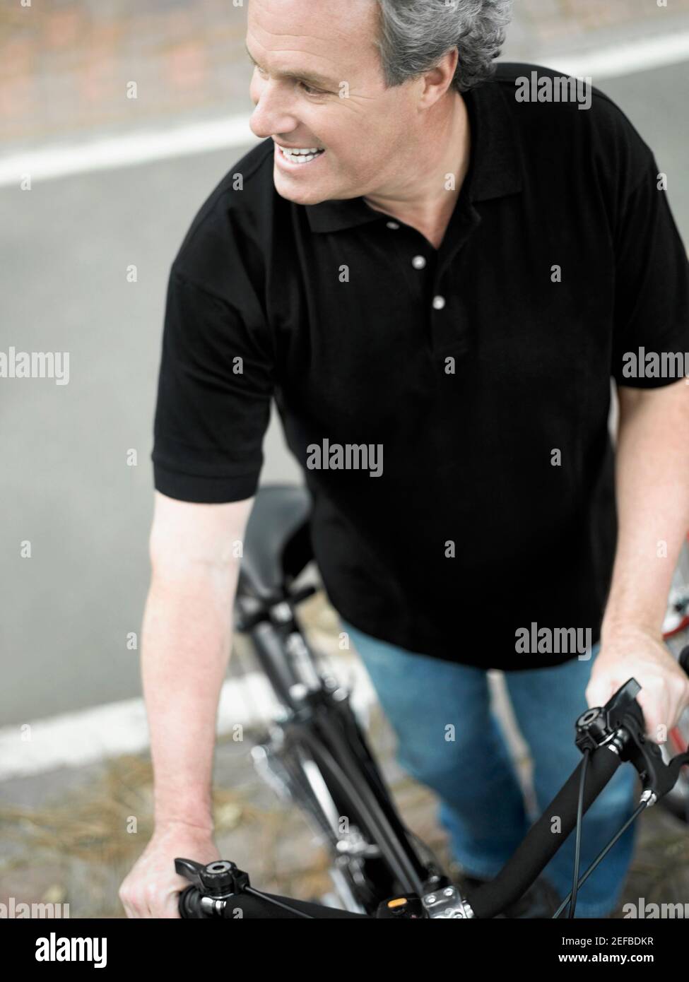 High angle view of a mature man standing with a bicycle and smiling Stock Photo
