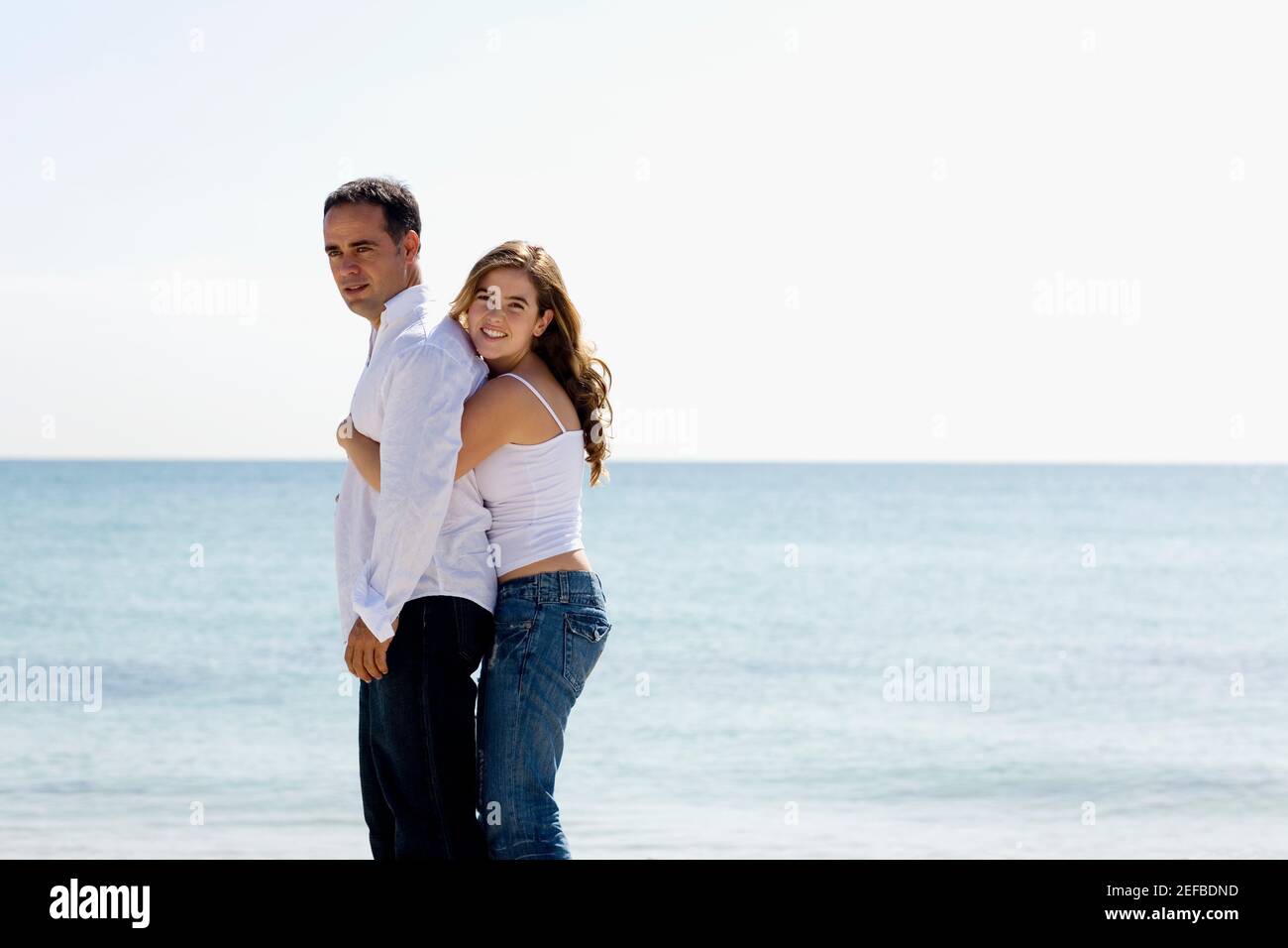 Side profile of a young woman embracing a mid adult man from behind ...