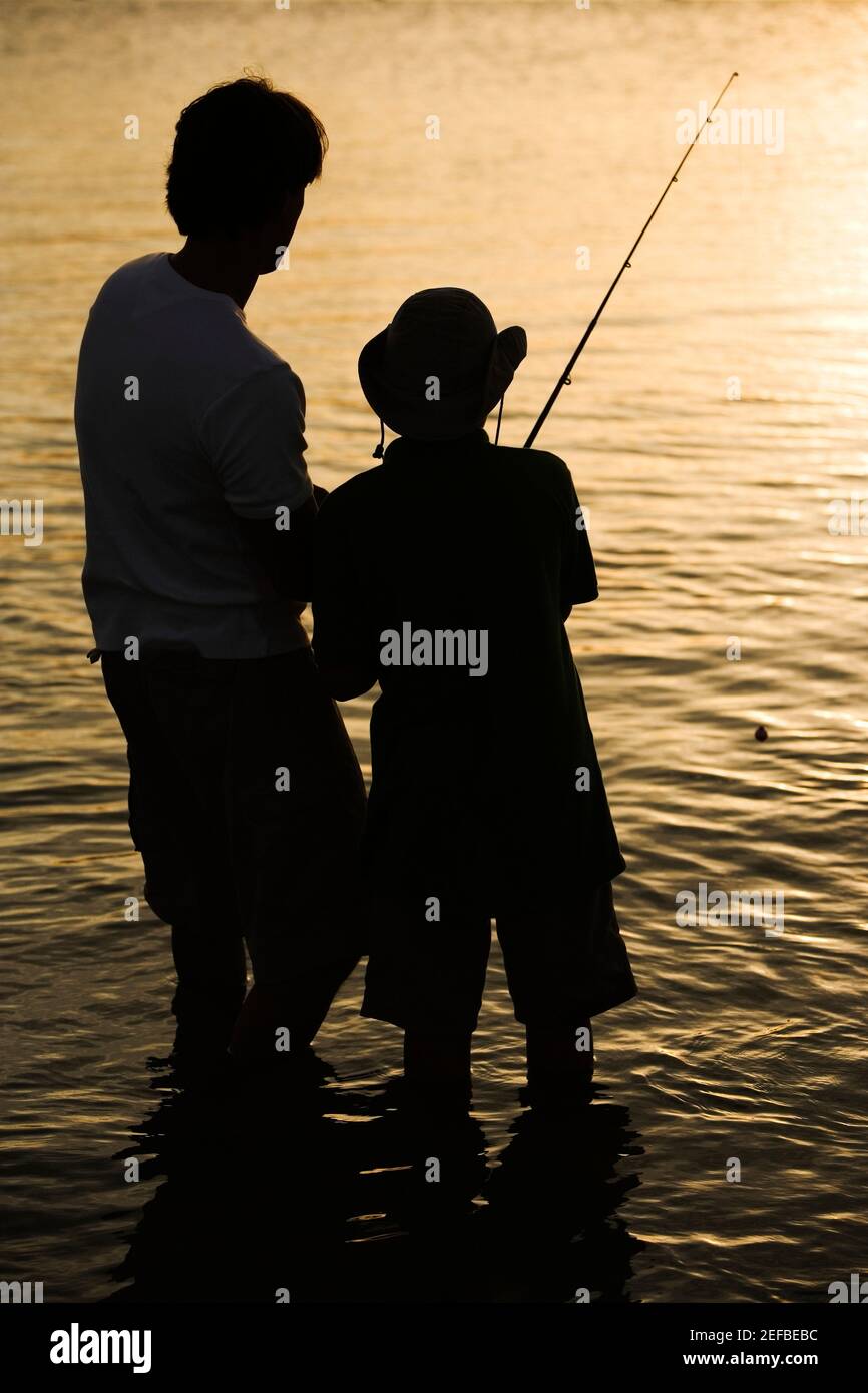 Silhouette of a father and his son fishing Stock Photo - Alamy