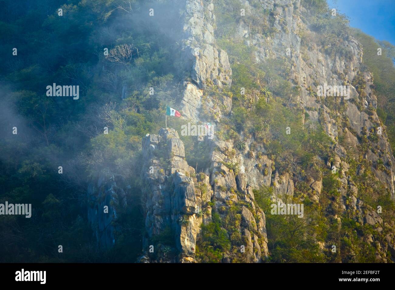 Low angle view of Mexican flag fluttering on a mountain, Waterfalls of the Monkeys, City Valleys, San Luis Potosi, Mexico Stock Photo