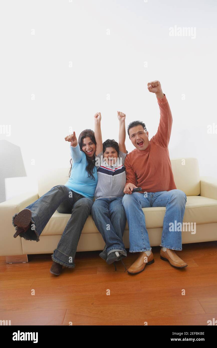 Mid adult man and a young woman with their son sitting on a couch and ...