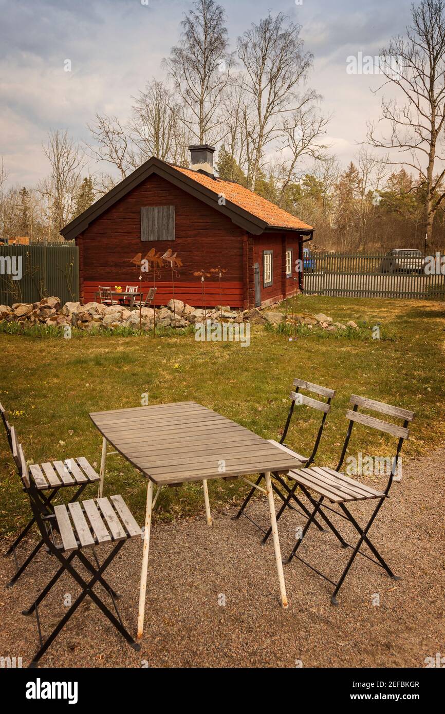 Small cottage in rural setting, with cafe table and chairs. Stock Photo