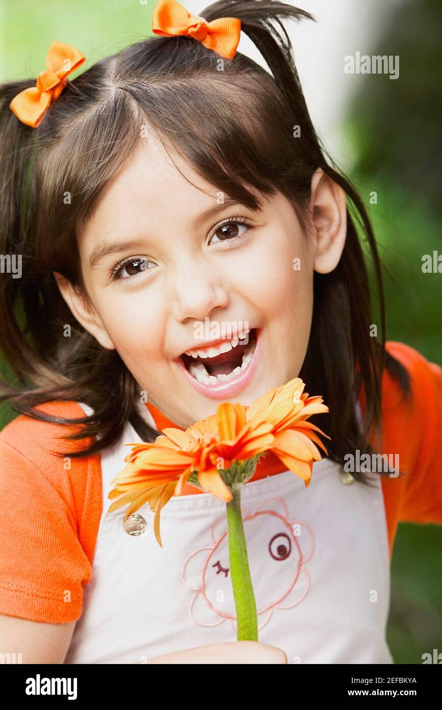 Portrait of a girl holding a flower and smiling Stock Photo - Alamy