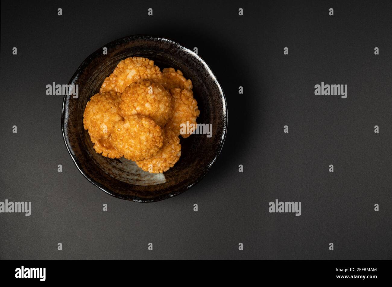 fried crispy rice crackers called rice age with soy,salt sugar etc flavor on black background is a traditional japanese snack. Stock Photo