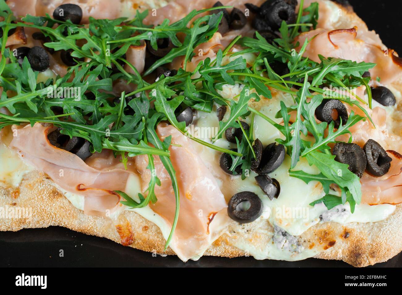 Pinsa romana close-up. gourmet italian cuisine on black background.  Scrocchiarella traditional dish. Food delivery from pizzeria. Pinsa with  meat, aru Stock Photo - Alamy