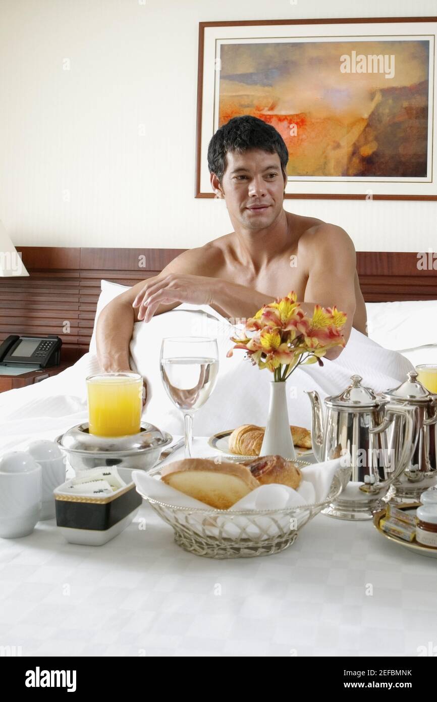 Mid adult man sitting on the bed with breakfast in front of him Stock ...