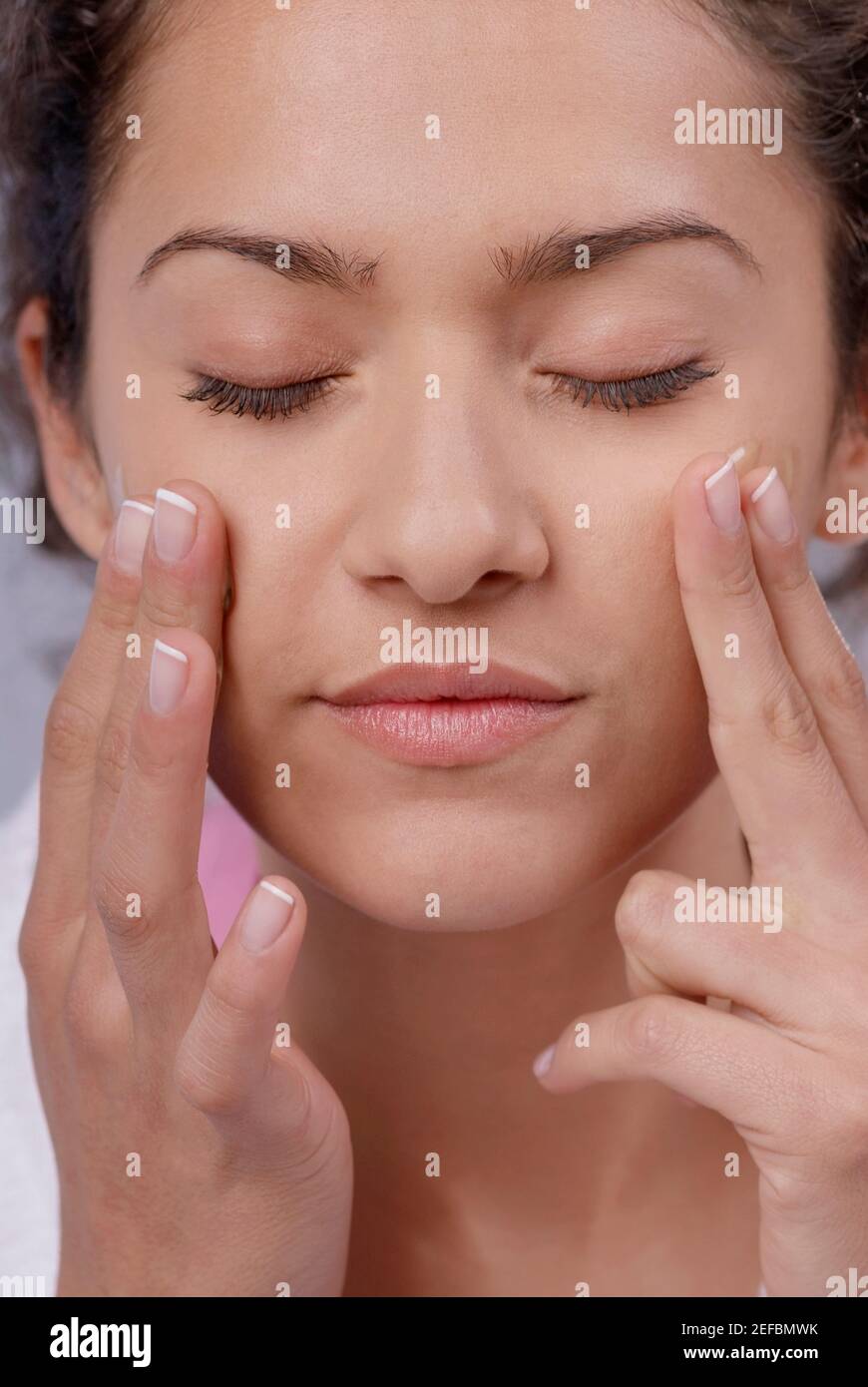 Close-up of a young woman applying moisturizer on her cheeks Stock Photo