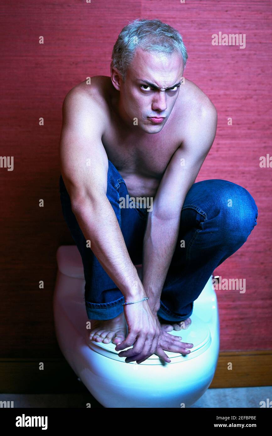 Portrait of a young man crouching on a toilet bowl Stock Photo Alamy