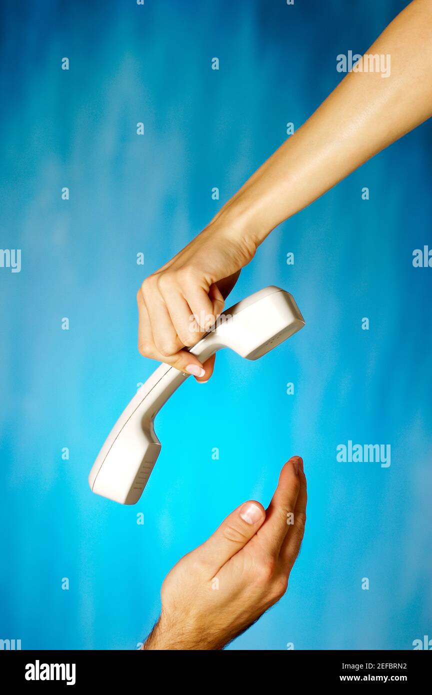 Close-up of a womanÅ½s hand holding a telephone receiver above a manÅ½s hand Stock Photo