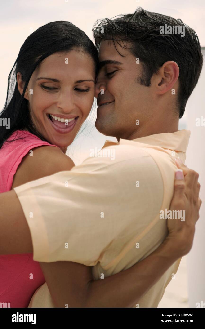 Side profile of a young woman and a mid adult man embracing each other ...
