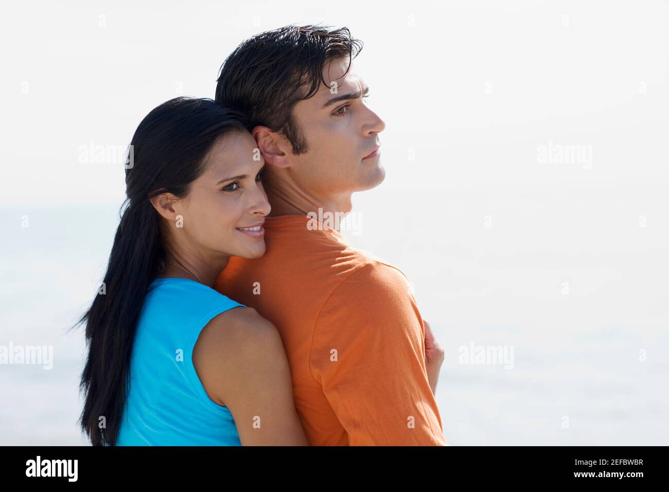 Side profile of a young woman embracing a mid adult man from behind ...