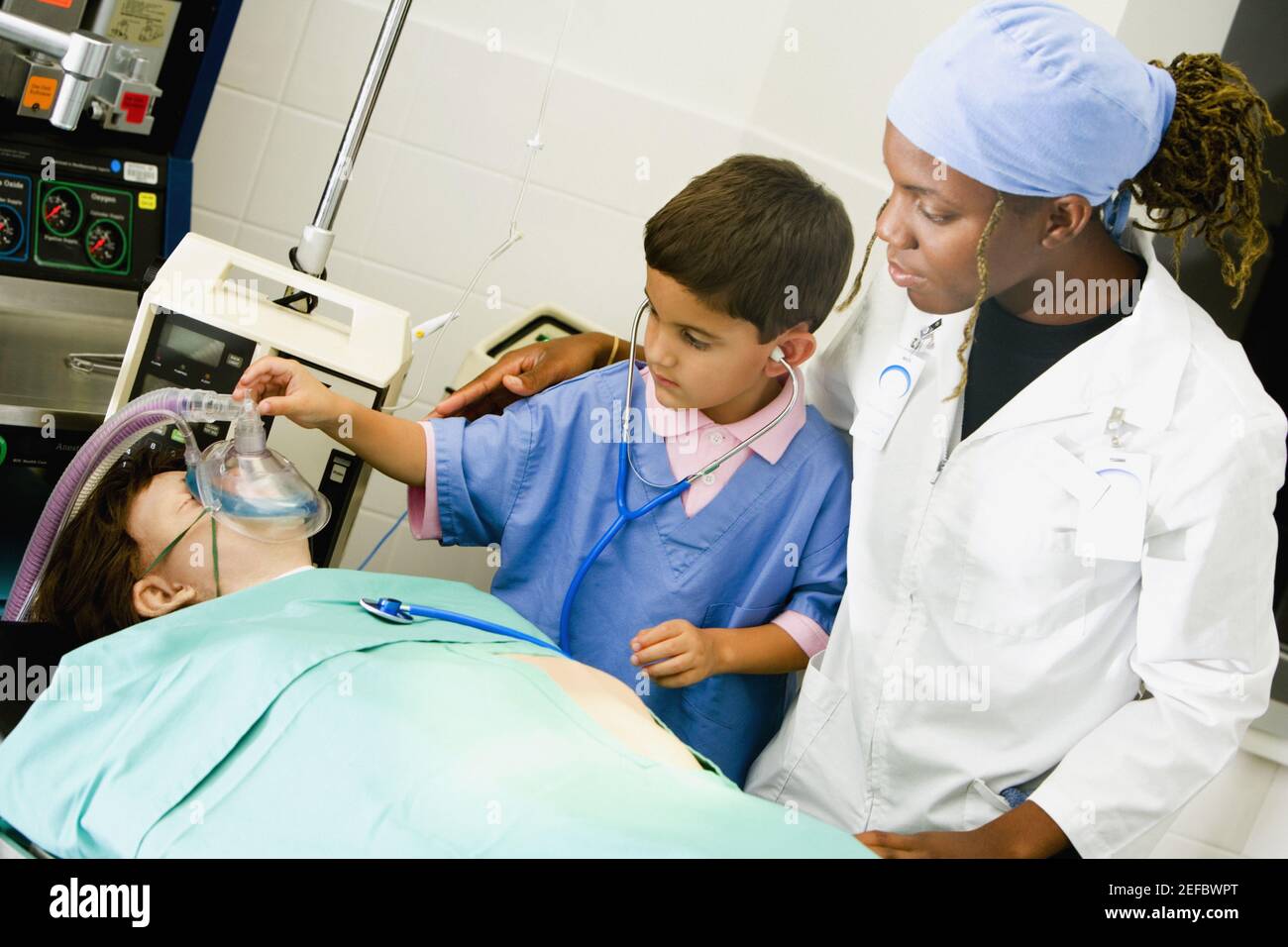 Boy imitating a doctor and adjusting the oxygen mask of a patient with