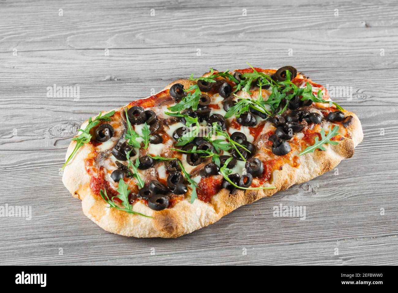 Pinsa romana gourmet italian cuisine on grey wooden background.  Scrocchiarella traditional dish. Food delivery from pizzeria. Pinsa with  meat, arugula Stock Photo - Alamy