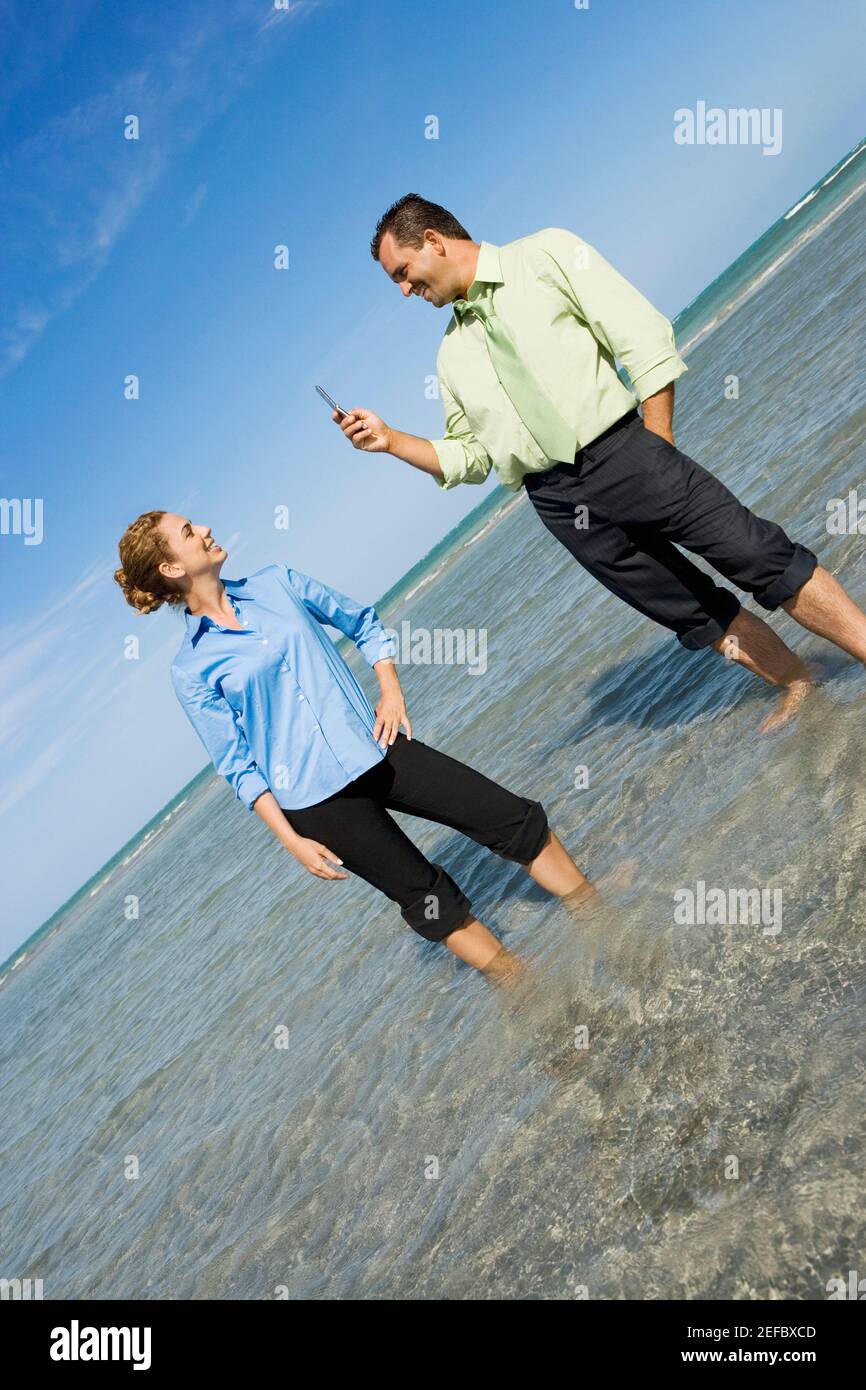 Mid adult man taking a photograph of a mid adult woman on the beach Stock Photo