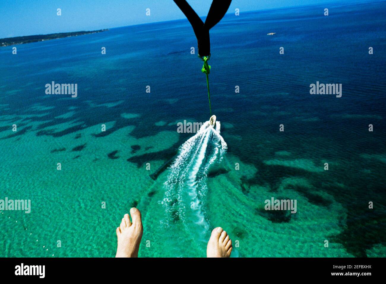 A mans feet are seen as he parasail over Negril Beach, Jamaica Stock Photo