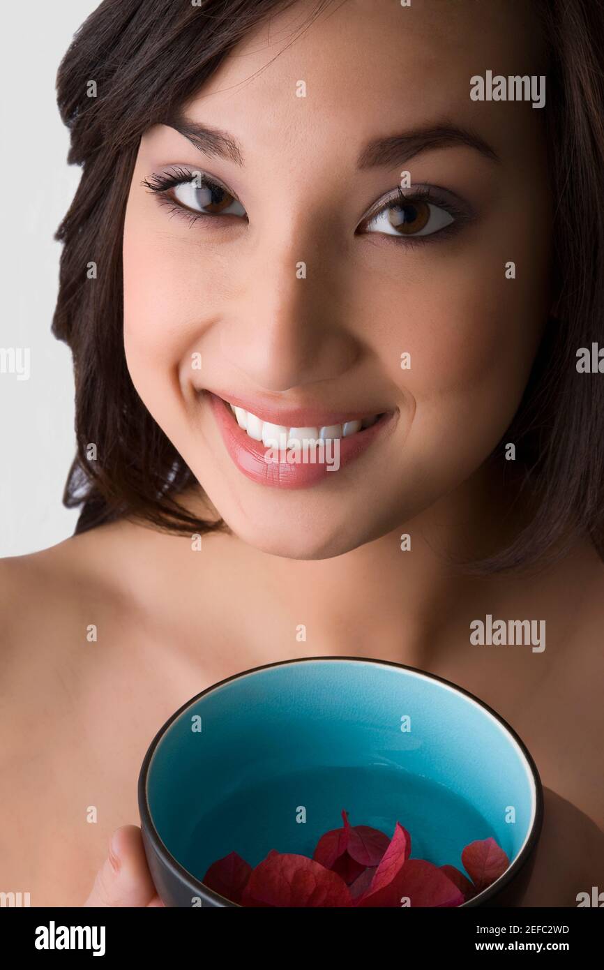 Portrait of a young woman holding a bowl of water with floating leaves Stock Photo