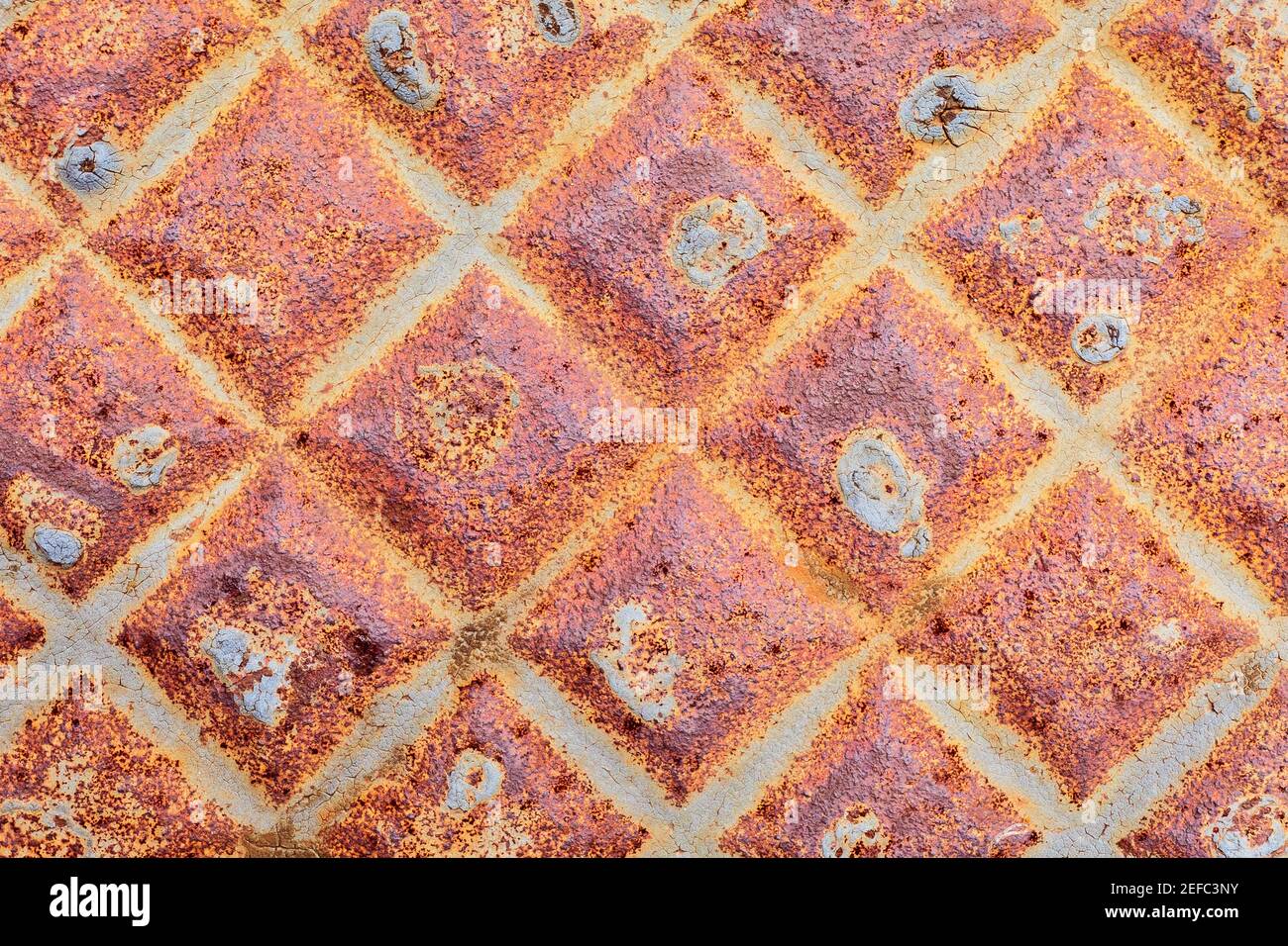 Close up image of a weathered manhole, showing its symmetrical pattern. Stock Photo