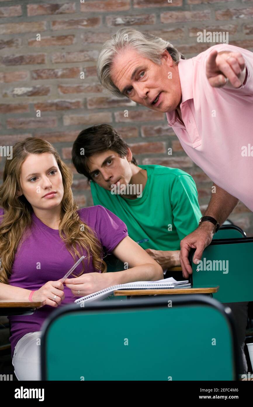 Professor assisting his students in a classroom Stock Photo