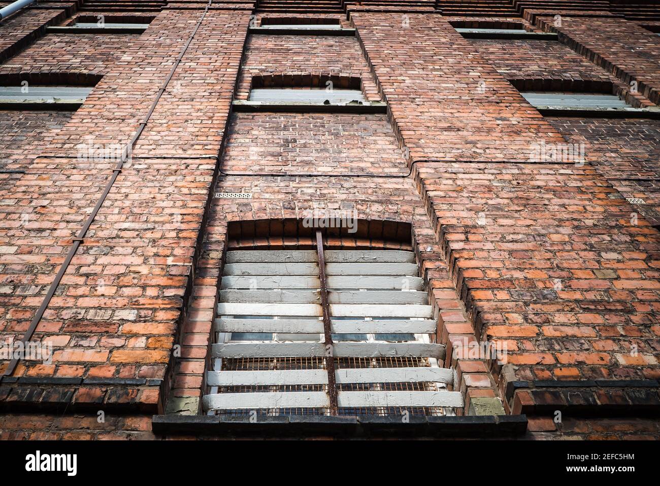 Victorian old red brick prison jail with bars over cell windows of high security run down immigration detention centre in England looking up exterior Stock Photo
