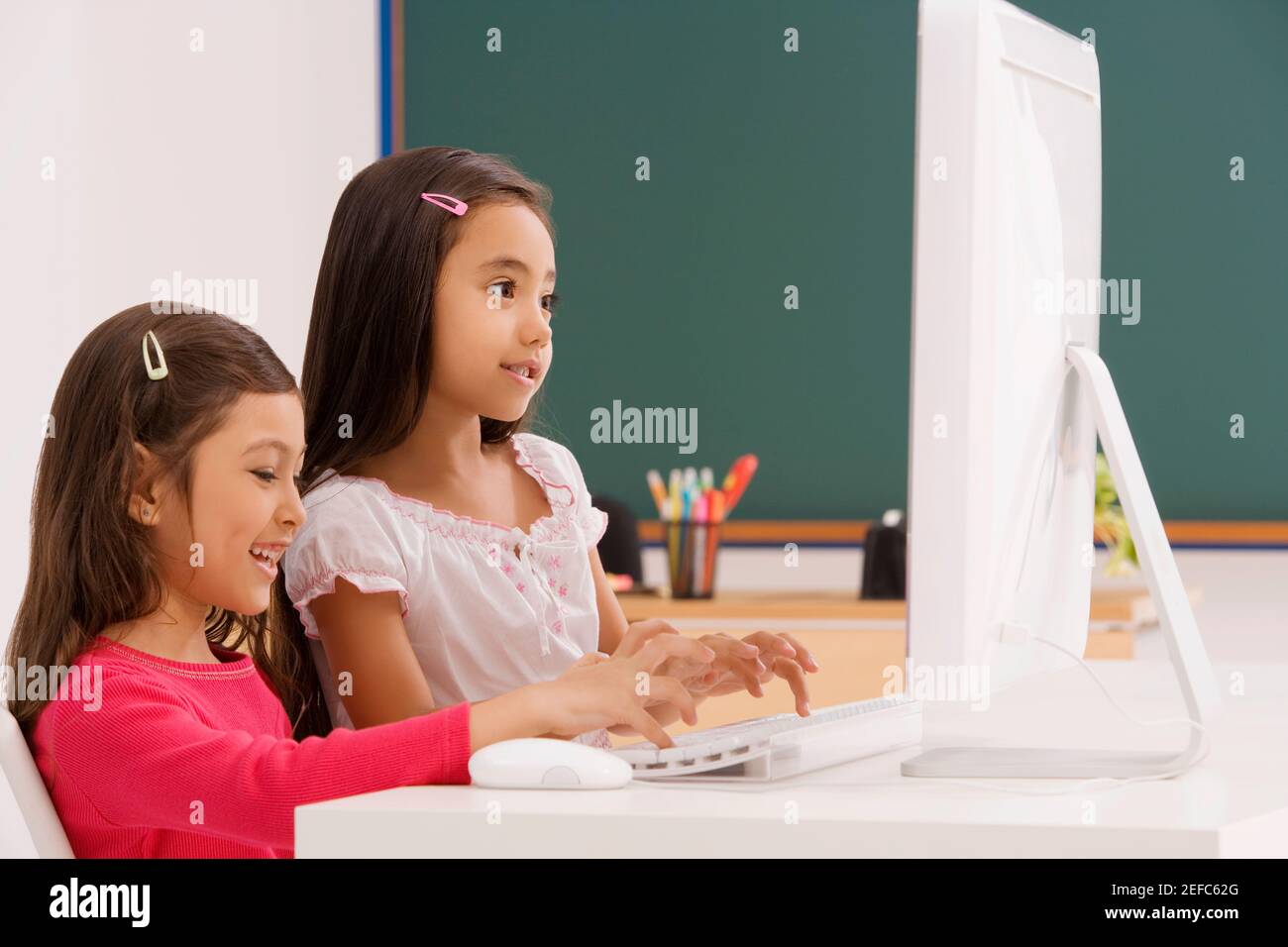 Side profile of a two schoolgirls using a computer in a classroom Stock ...