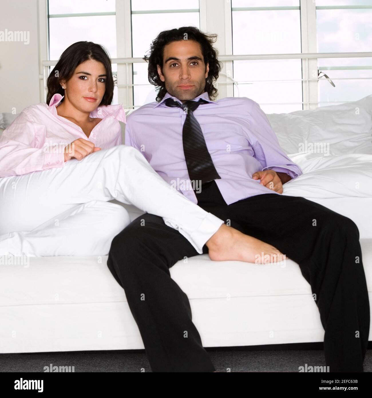 Portrait of a young woman and a mid adult man sitting on the bed Stock ...