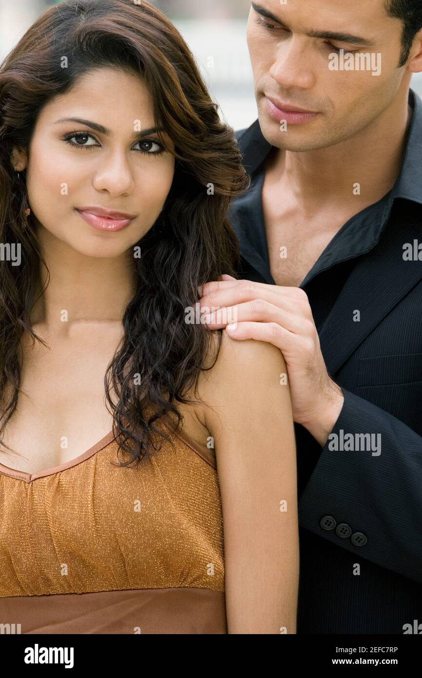 Portrait of a young woman smirking with a mid adult man standing behind ...