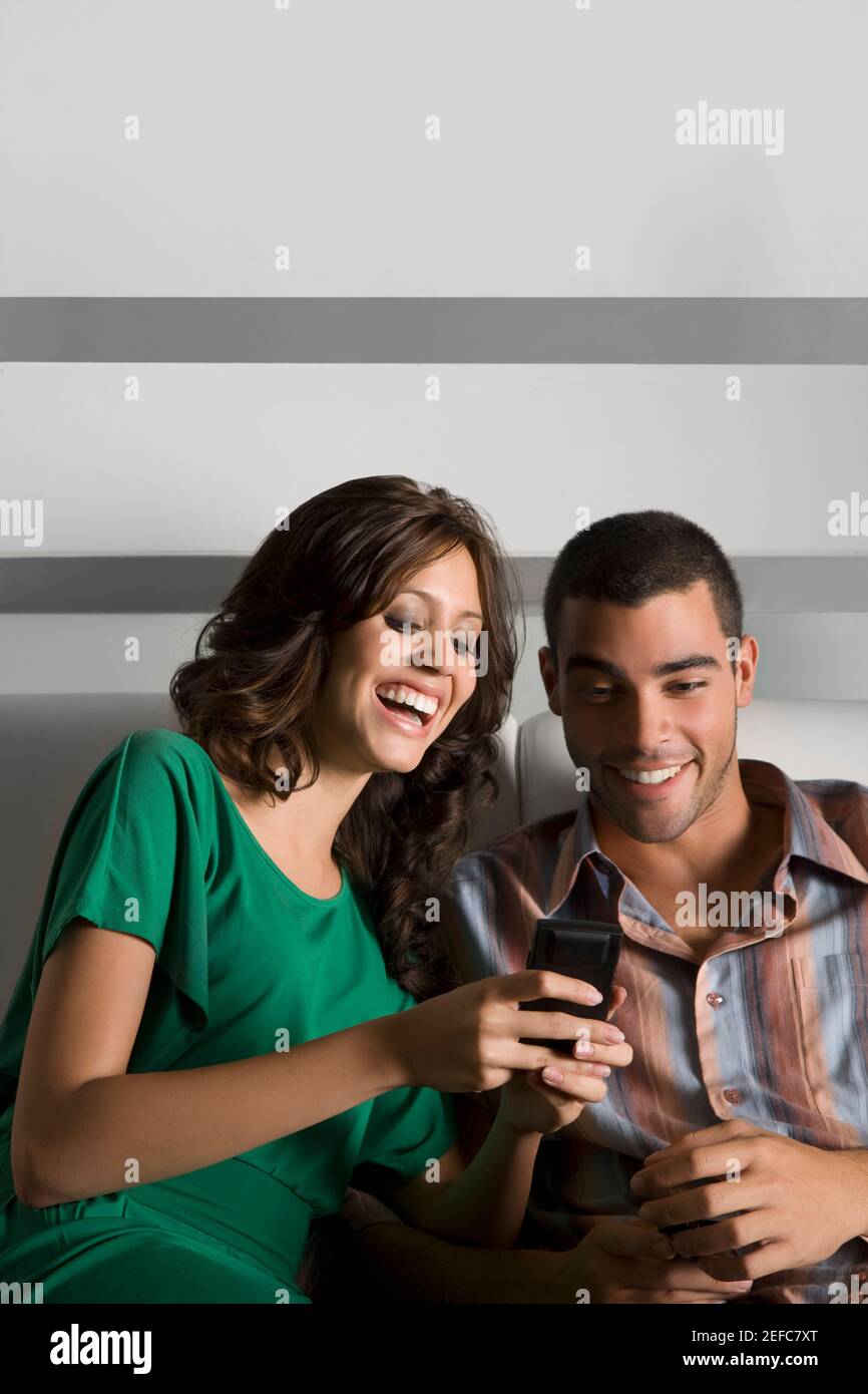 Young couple using a mobile phone and smiling Stock Photo