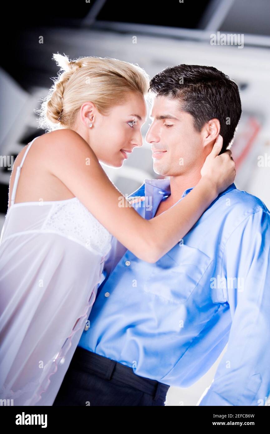 Side profile of a young woman and a mid adult man embracing each other ...