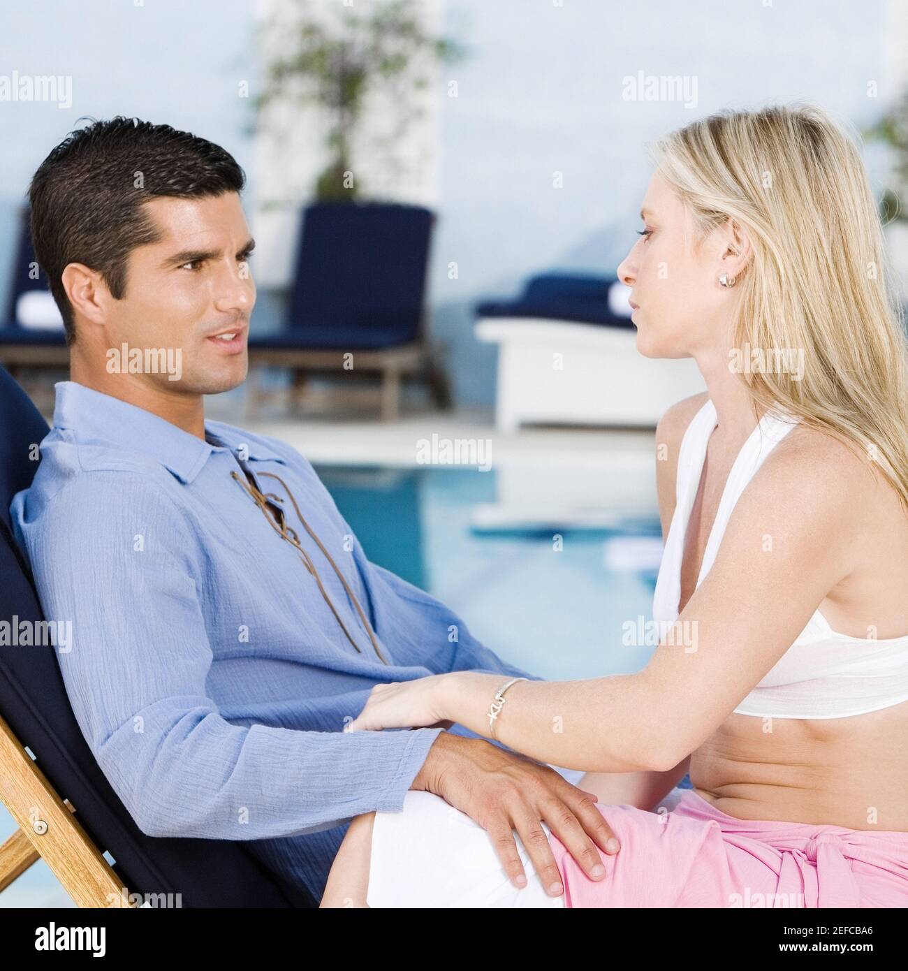 Side profile of a young woman and a mid adult man sitting on a deck ...