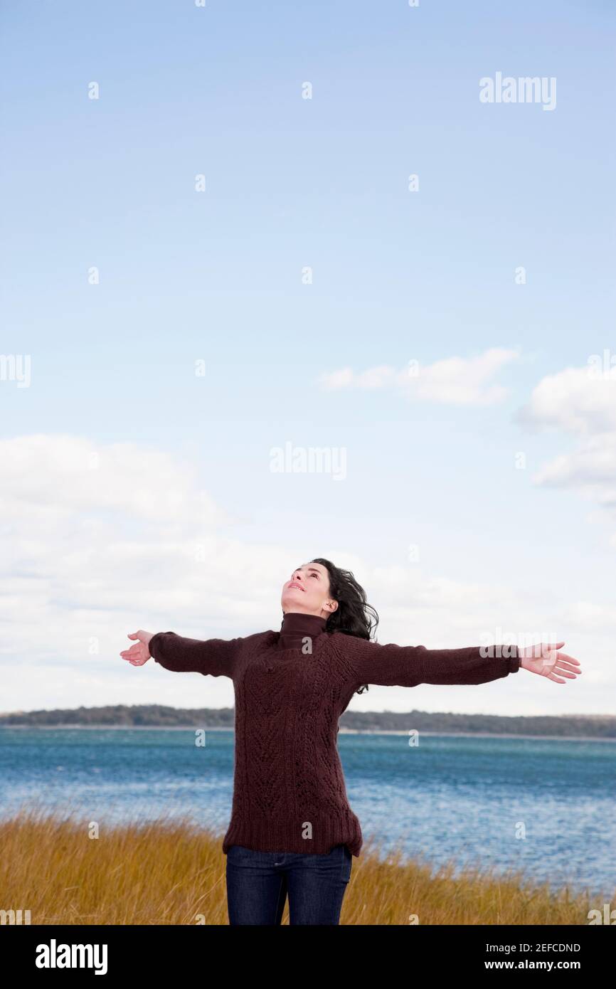 Mature woman standing on the beach with her arms outstretched Stock Photo