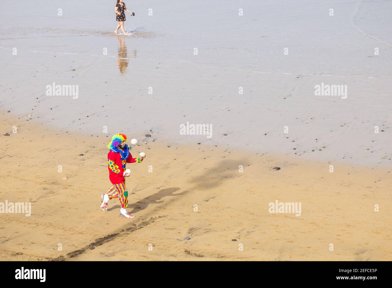 Las Palmas, Gran Canaria, Canary Islands, Spain. 17th February, 2021. Despite the cancellation of the month long carnival in Las Palmas (due to Covid), people still head out in costumes, like this clown juggling on the city beach with temperatures close to 30 degrees Celsius. Credit: Alan Dawson/Alamy Live News. Stock Photo