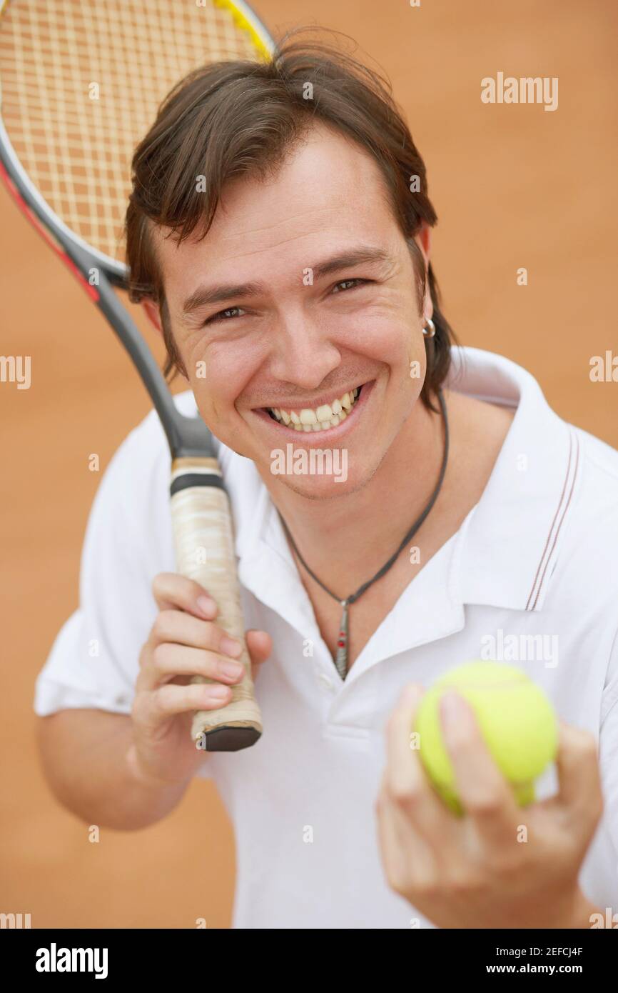 Portrait of a mid adult man holding tennis balls and a tennis racket