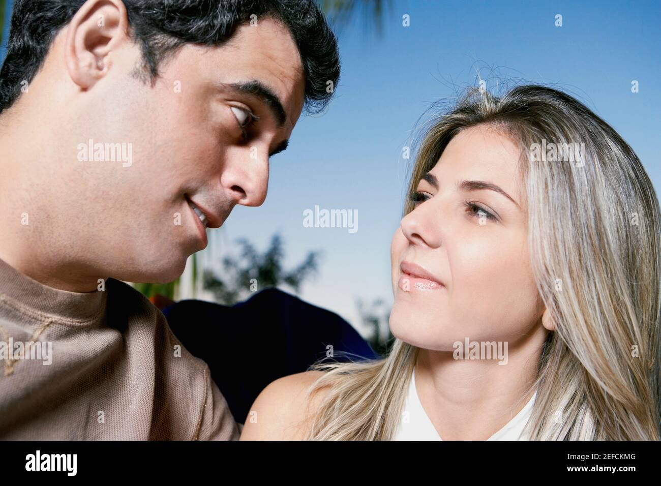 Close up of a mid adult man and a mid adult woman looking at each other ...